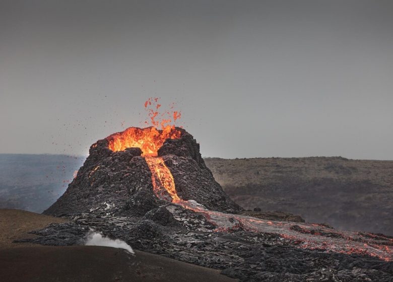 belle-photo-volcan-actif-lave-qui-coule-fumee-sous-ciel-clair_181624-56865